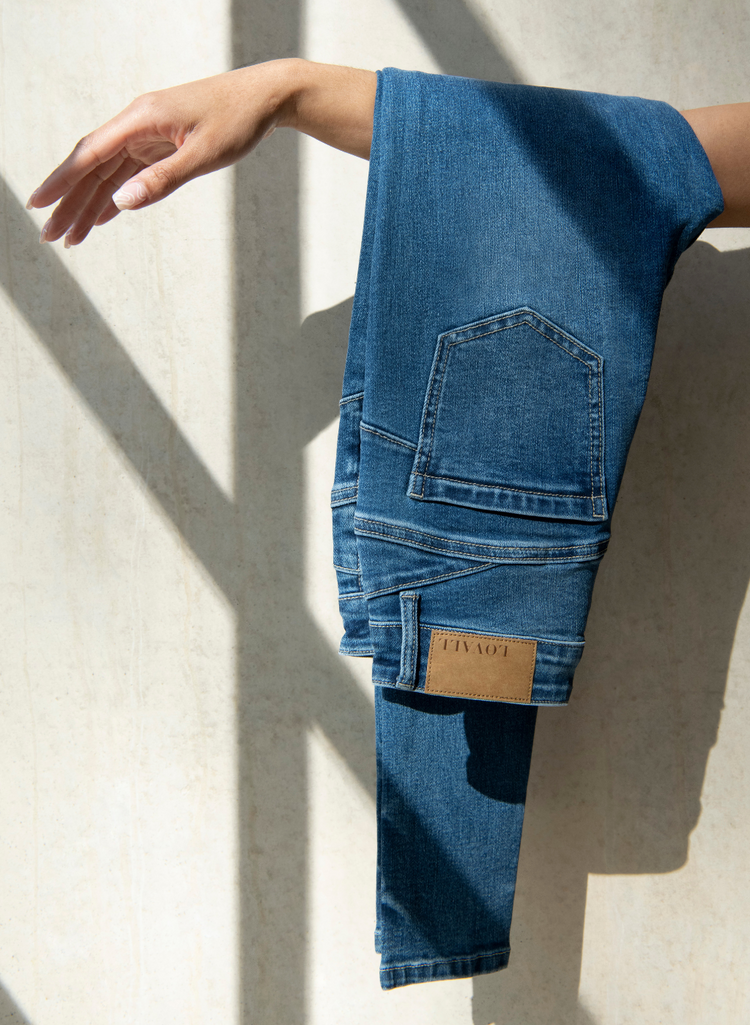 LOVALL Denim Jeans folded over a woman's arm.